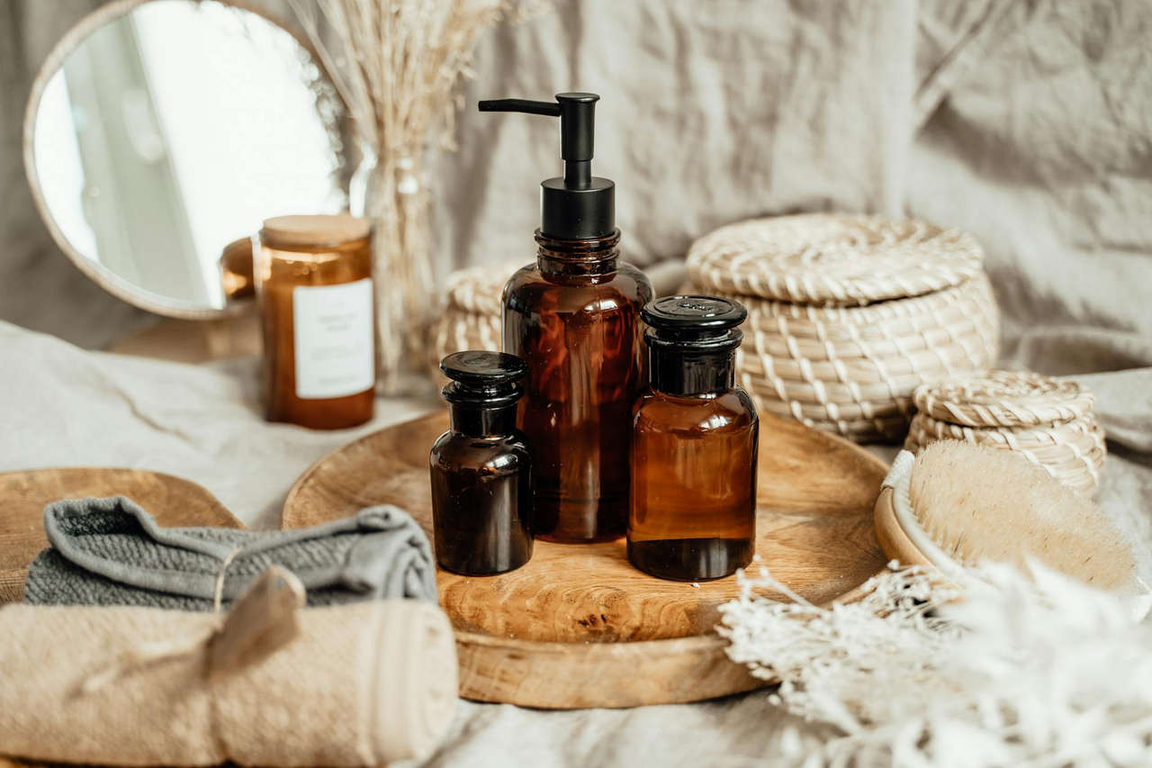 Aesthetic display of brown glass bottles and woven containers on a wooden tray.